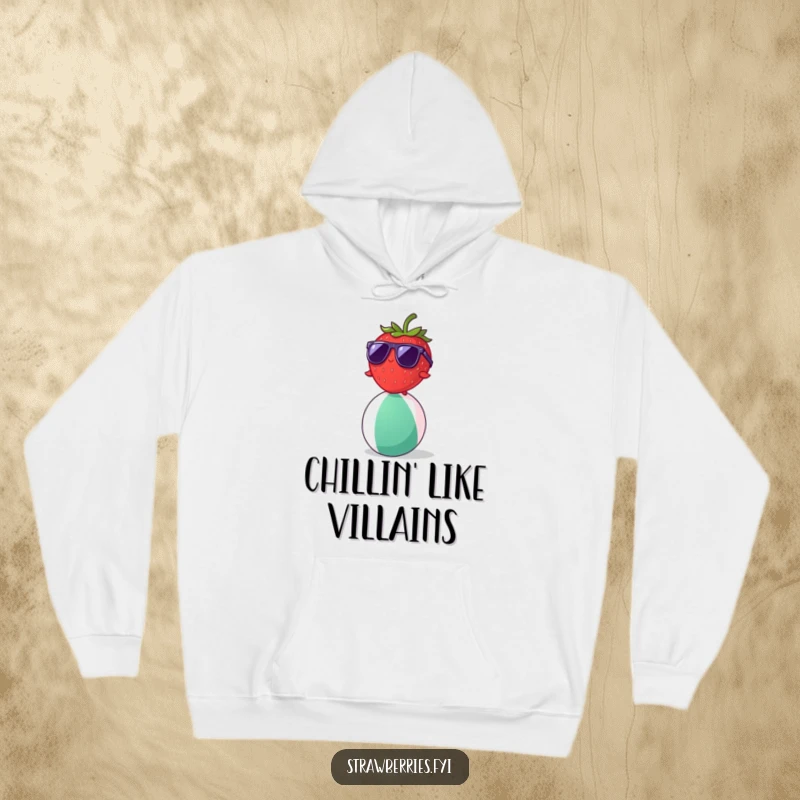 Funny strawberry character with sunglasses balancing on a beach ball, depicted on a cozy hoodie.